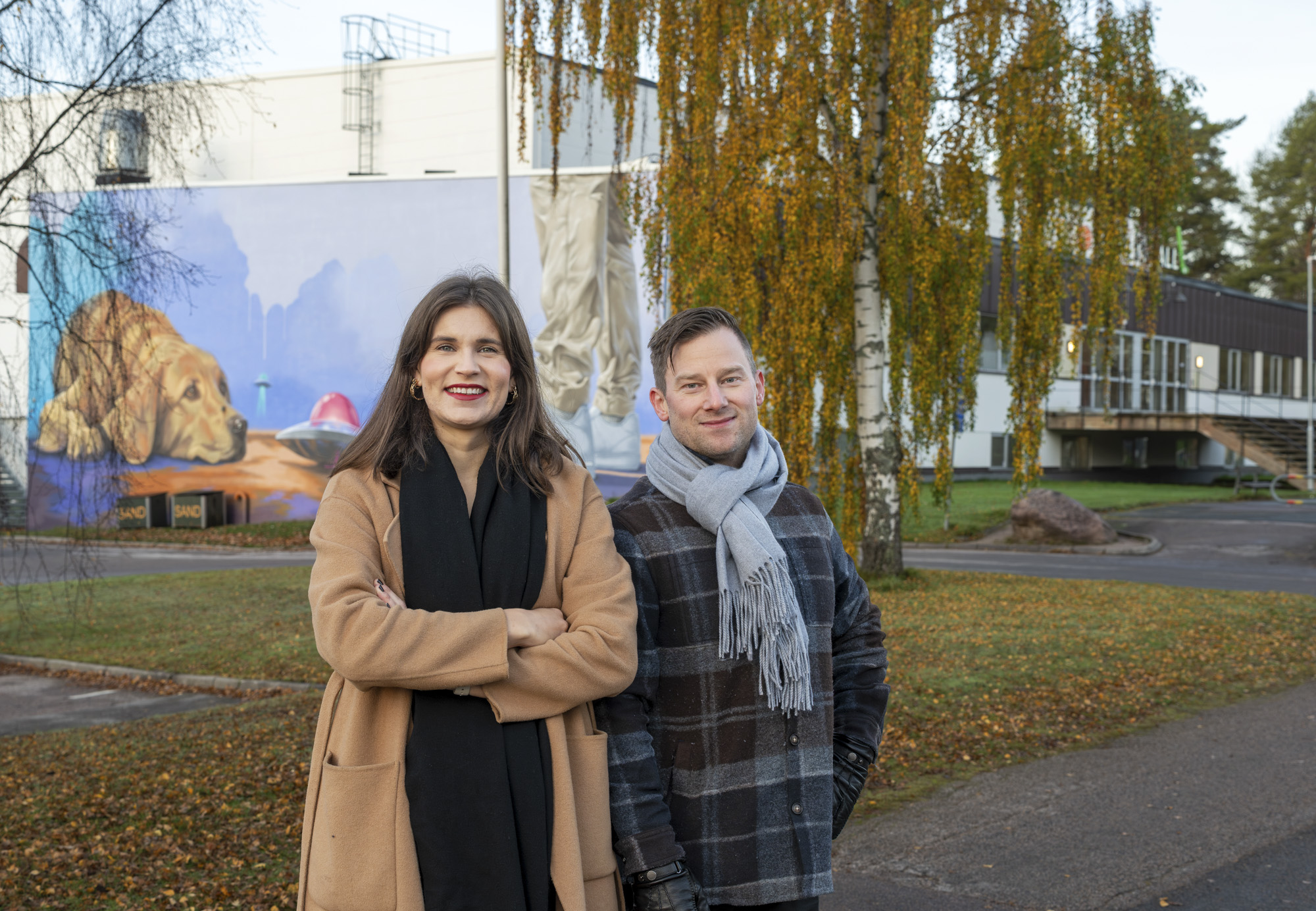 Man och kvinna utomhus med höstfärgade träd i bakgrunden